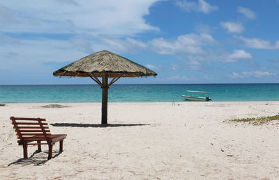 Deck chairs on beach against sky