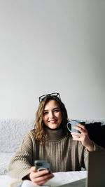 Portrait of young woman using mobile phone while sitting at home