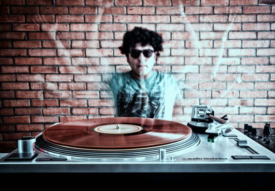 Multiple exposure of man with turntable against brick wall