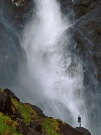 Man standing by waterfall