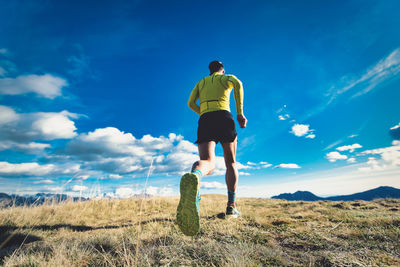 Rear view of man standing on field against sky