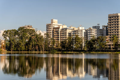 Buildings by lake against clear sky