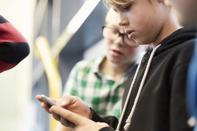 Middle school boy using mobile phone with friends in corridor