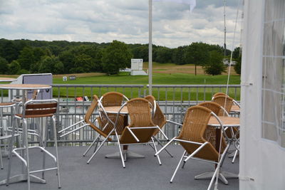 Empty chairs and table against golf course