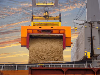 Yellow machine part against sky during sunset