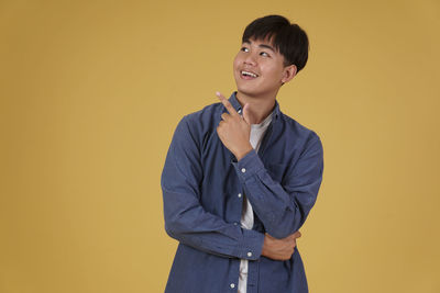 Portrait of smiling man standing against yellow background