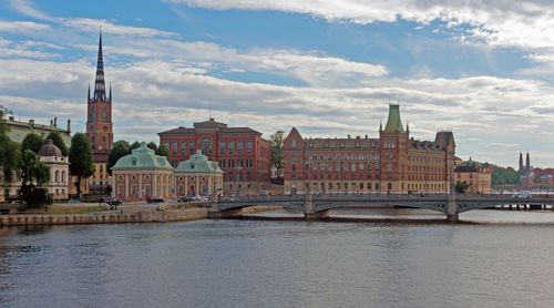 Bridge over river by buildings against sky in city