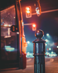 Bollard on road against illuminated street lights