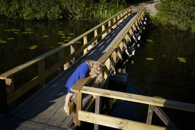 High angle view of toddler on footbridge over lake