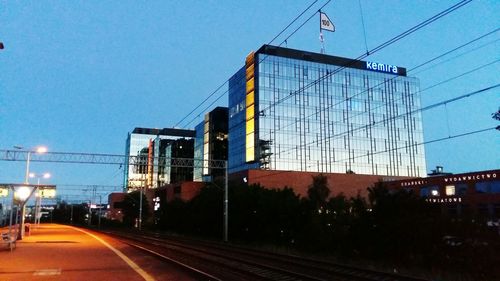 Road by illuminated city against clear sky