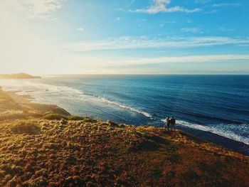 High angle view of couple on cliff by sea against sky