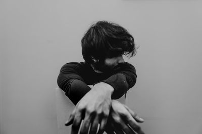 Side view of a man sitting against wall