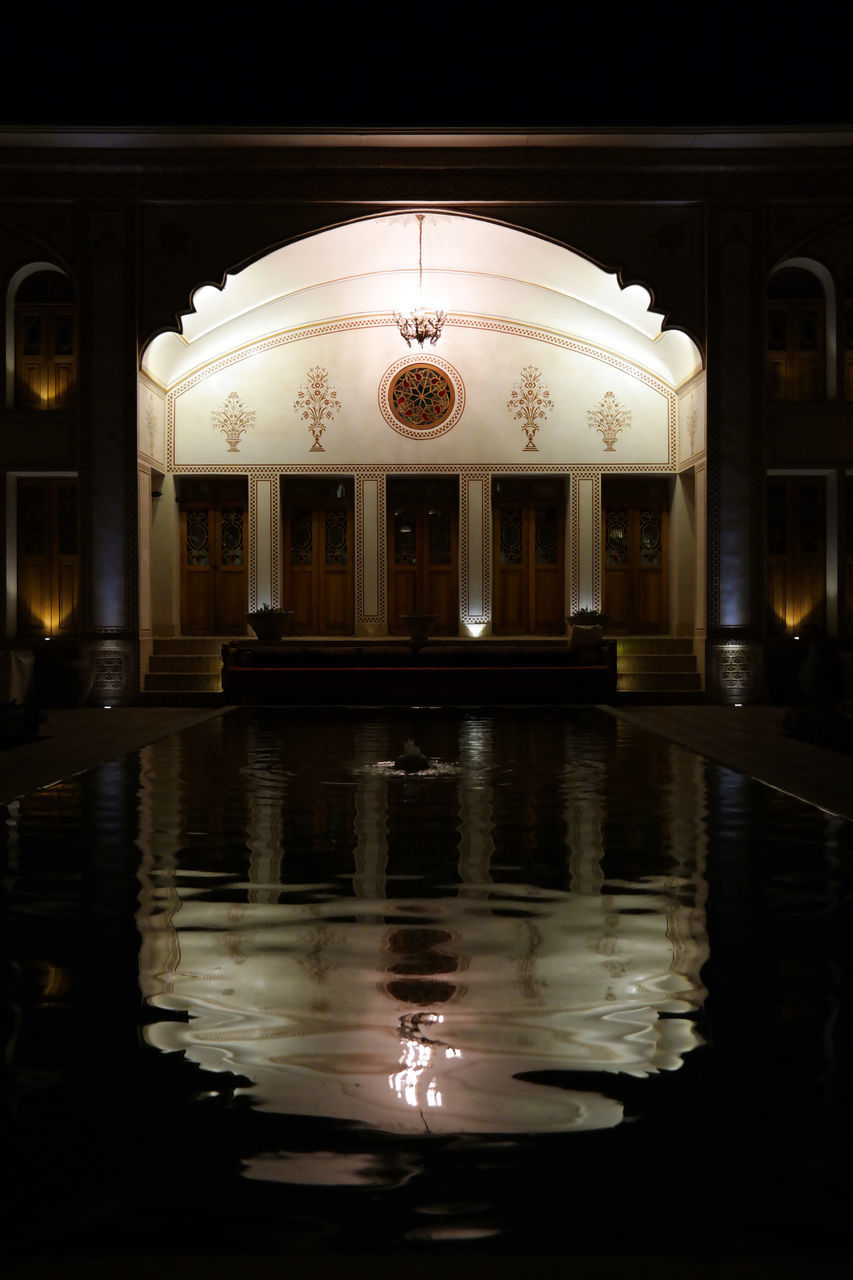 REFLECTION OF ILLUMINATED BUILDING ON WATER AT NIGHT