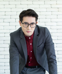 Portrait of young businessman standing against wall