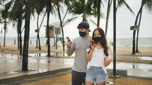 Young man and young woman looking at a smartphone at the beach 