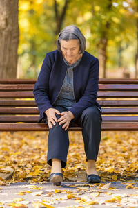 Woman with knee pain sitting on bench at park