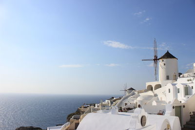 Traditional windmill by sea against sky