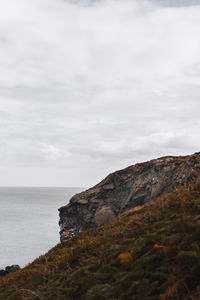 Scenic view of rocks by sea against sky