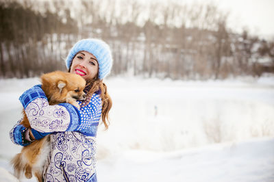 Portrait of woman with puppy standing on snow