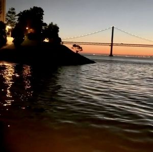 Portrait of bridge over river against sky at sunset