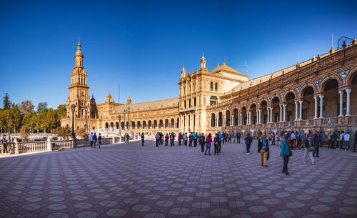 Group of people in front of building against blue sky