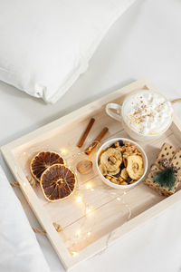 Christmas breakfast on a white wooden tray decorated with festive decor and garland. 