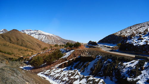 Scenic view of snowcapped mountains against clear blue sky