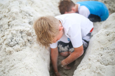 Siblings digging sand with hands