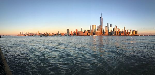 Sea and buildings in city against clear sky