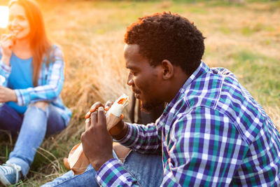 Rear view of man and woman sitting on field