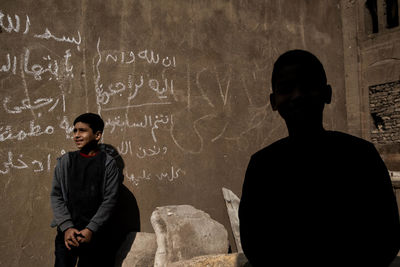 Rear view of friends standing against wall in building