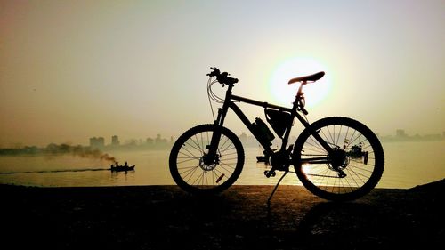 Silhouette bicycle against sky during sunset