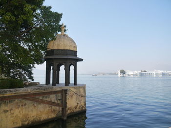 Gazebo by river against clear sky