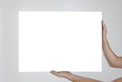 Midsection of woman holding paper against white background