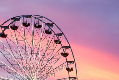 Low angle view of ferris wheel against sky during sunset