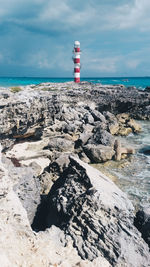 Lighthouse by sea against sky