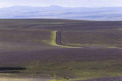 Woman standing in the middle of nowhere on dirt road in highlands