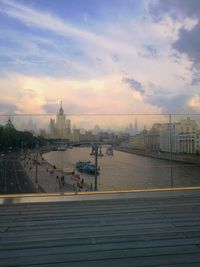 Bridge over river by buildings against sky during sunset