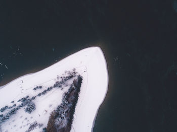 Aerial view of snow covered land by lake during winter