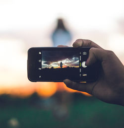 Man photographing camera on mobile phone against sky