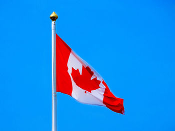 Low angle view of canadian flag against clear blue sky