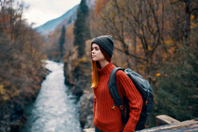 Young woman looking away while standing on land during winter