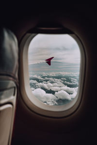 Airplane flying over clouds seen through window