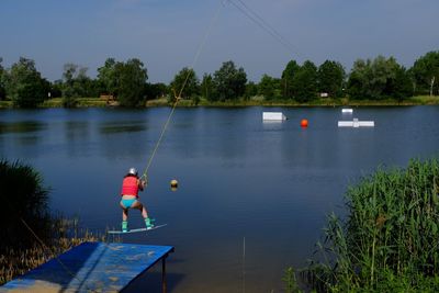 Man fishing in lake against sky