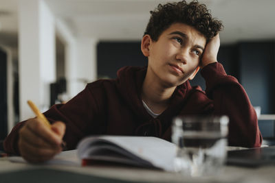 Confused boy with head in hand studying at home