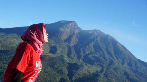 Side view of woman looking at mountains against sky