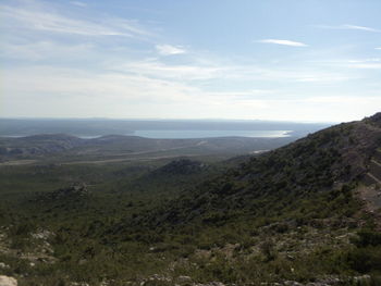 Scenic view of landscape by sea against sky