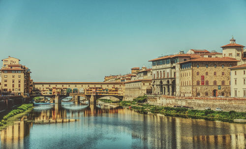 Arch bridge over river against buildings in city