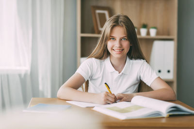A smiling girl does her homework, writes a synopsis, and prepares for lectures. 
