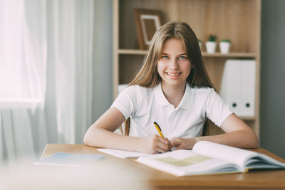 Portrait of smiling young woman sitting on table